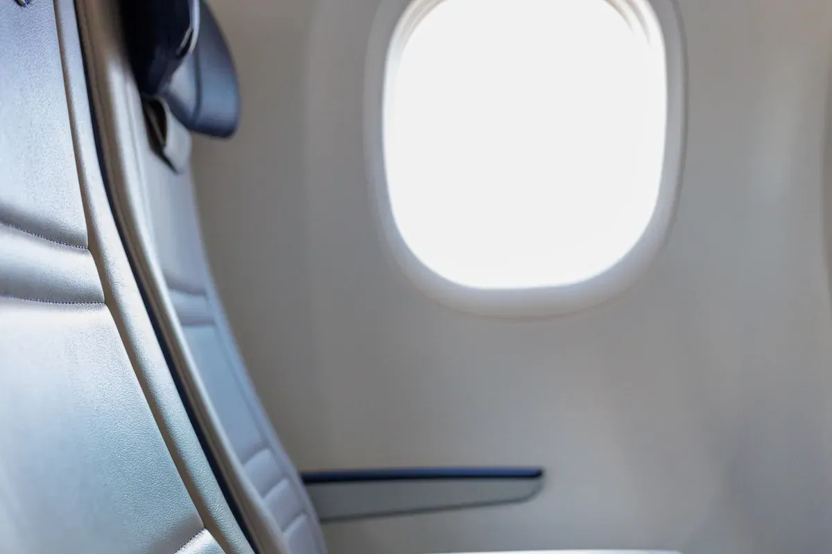 An airplane window seat with daylight coming through the cabin