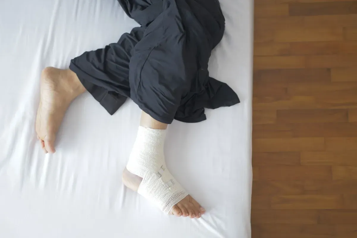 A bandaged foot resting on a bed
