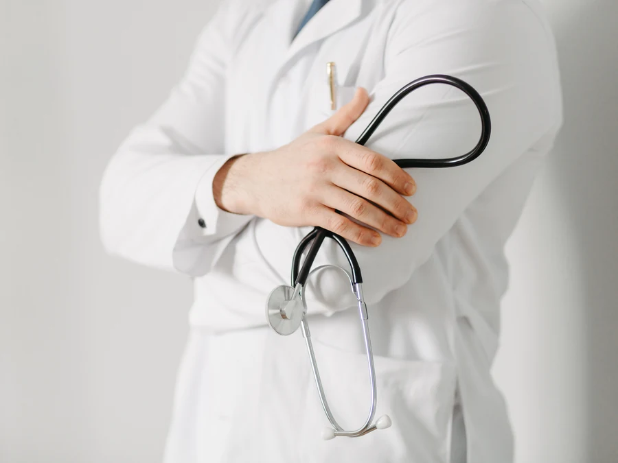 A physician in a white coat, arms folded, holding a stethoscope