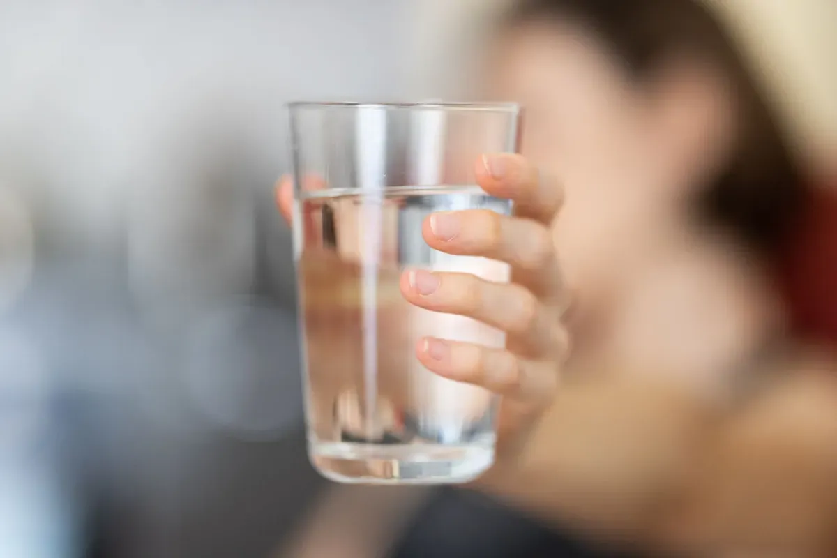A hand holding a glass of water