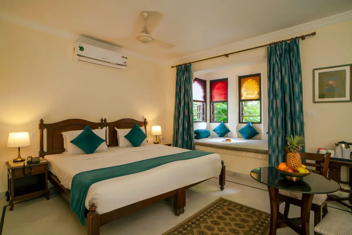 A made-up hotel room with a bed by the window
