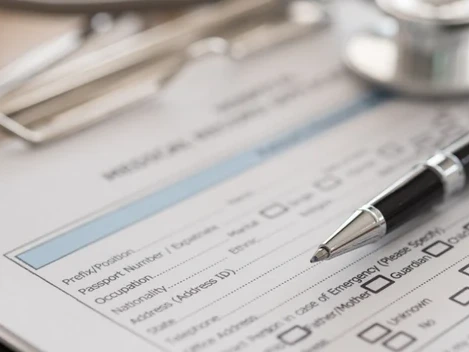 A medical form on a clipboard with a pen and stethoscope, of the kind used for an insurance claim