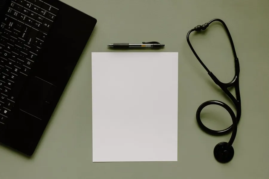 A stethoscope and notepad on a clinic desk