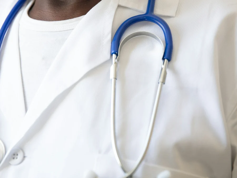 A physician's white coat with a stethoscope around the collar