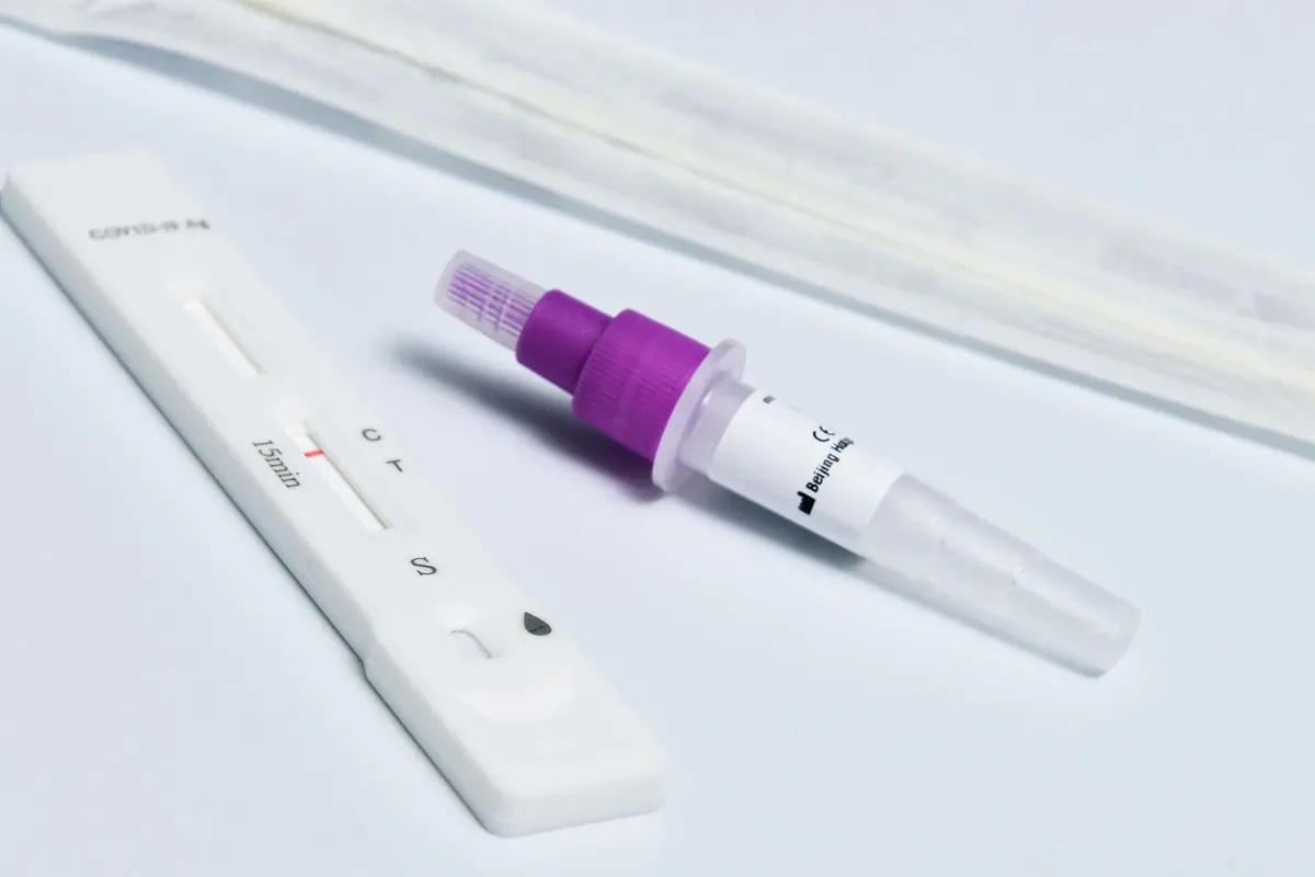 A rapid antigen test cassette and swab on a white surface