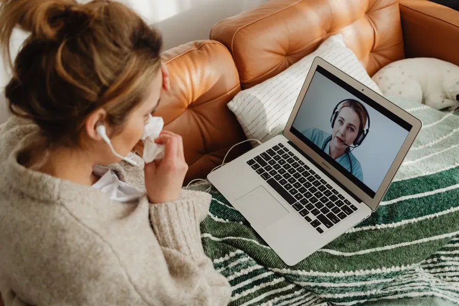 A traveler on a video consultation from her sofa